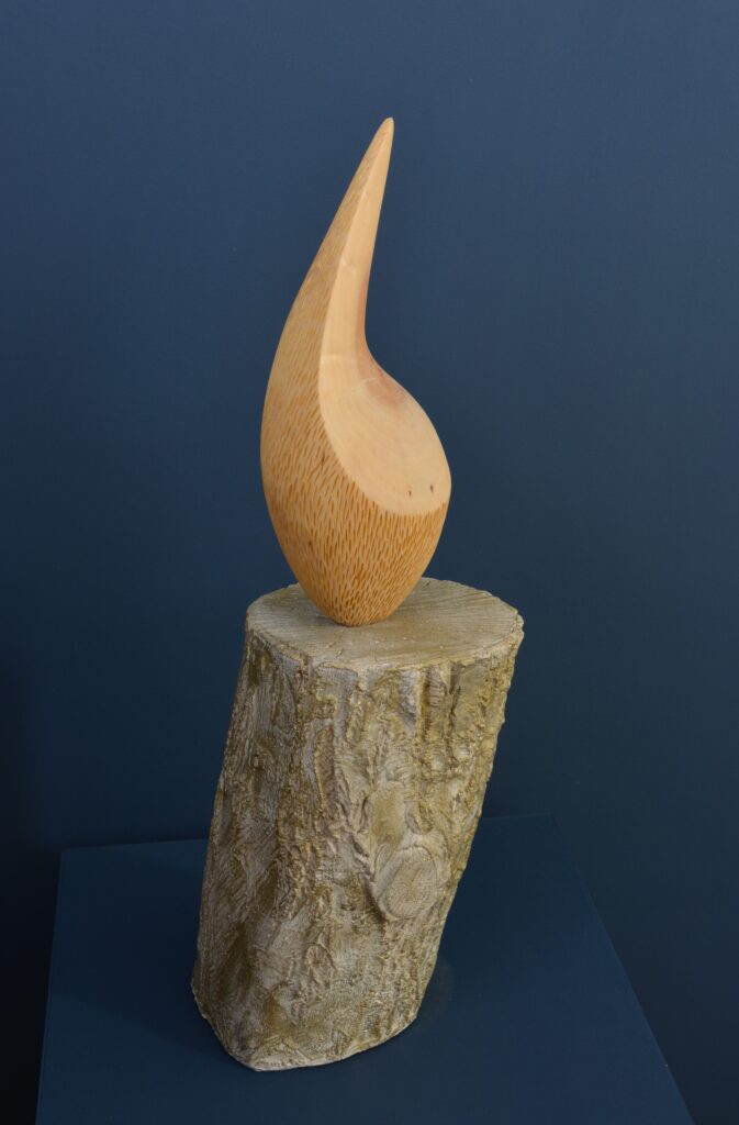Organically carved willow wood form with gold accents, mounted on a stone base.